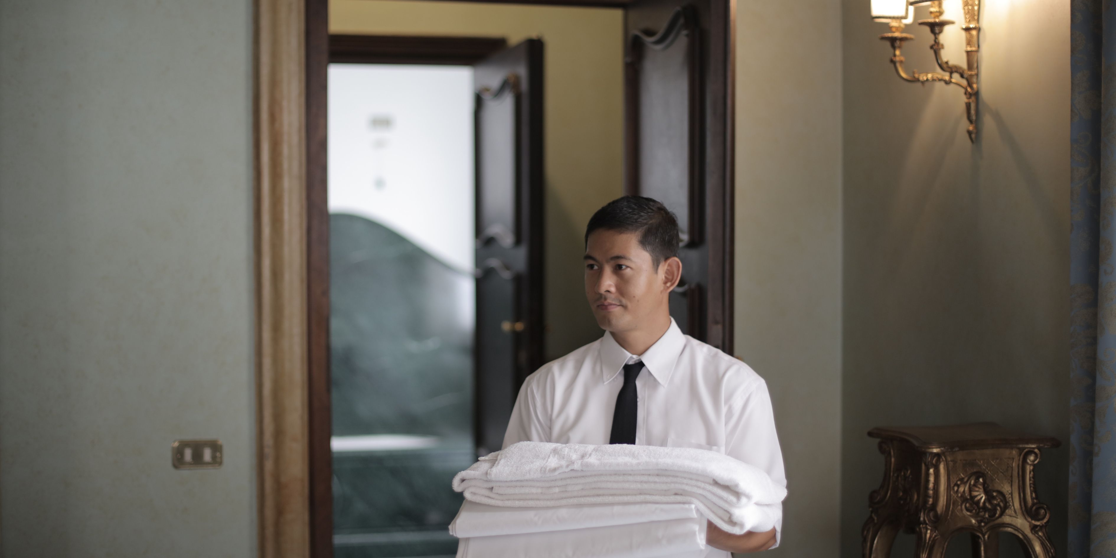 a service person carrying towels into  room